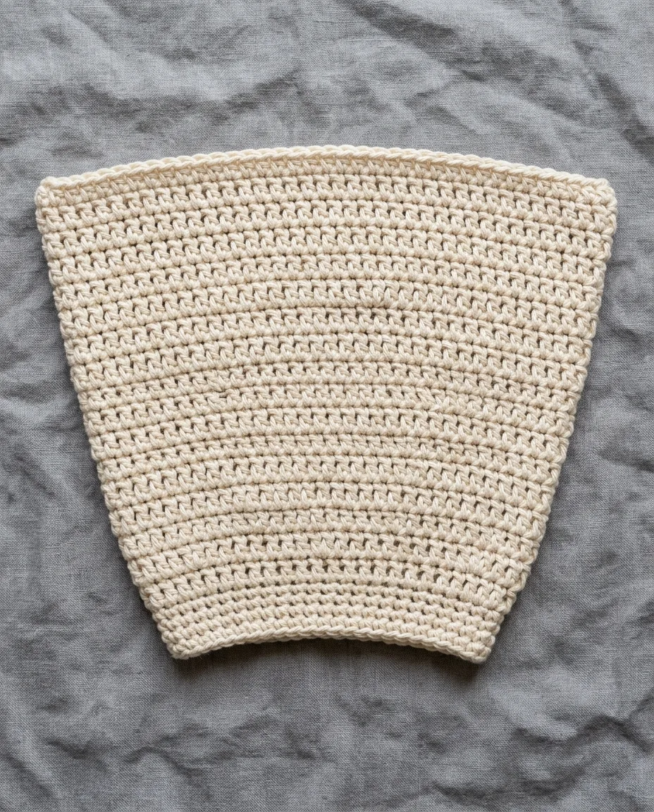 A rectangle whose starting chain came out shorter than its rows, so the bottom edge pulls in and the piece fans out.